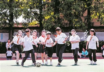 在无锡市广新小学操场上，随班就读学生小莹、小俊和同学们一起踢足球。阳光下，孩子们脸上绽放出灿烂的笑容。